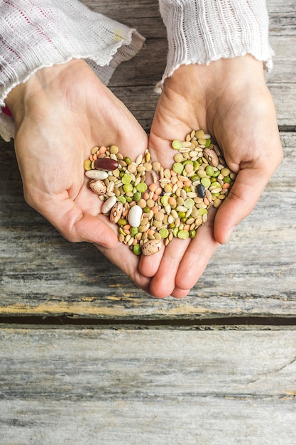 Free photo vertical closeup shot of female hands holding mixed beans