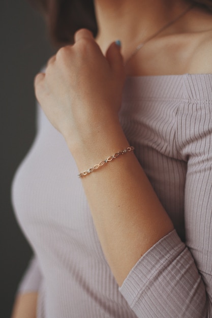 Vertical closeup shot of a female wearing a golden bracelet