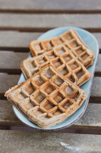 갓 구운 맛있는 와플의 수직 근접 촬영 샷은 신선한 공기에 흰 접시에 제공