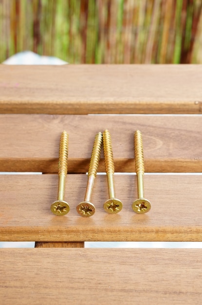 Free photo vertical closeup shot of golden cross screws on a golden table