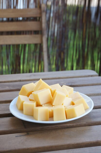 Vertical closeup shot of Gouda cheese blocks on a white plate on a wooden surface