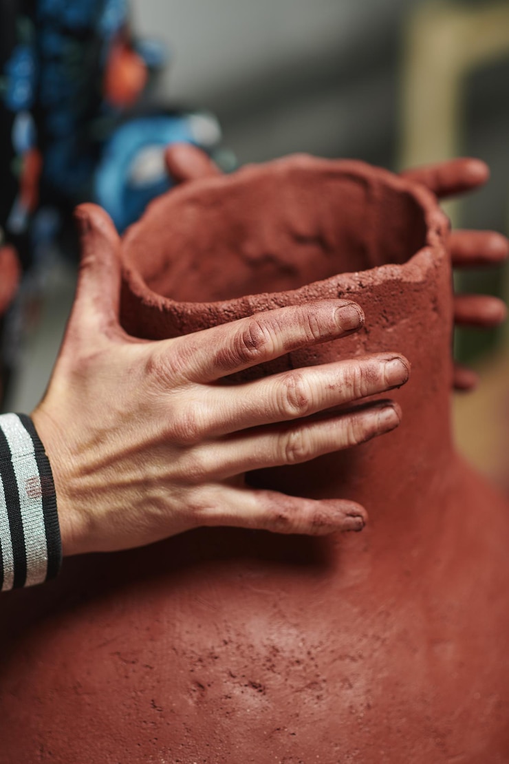Free Photo vertical closeup shot of hands sculpting a clay vase with a face
