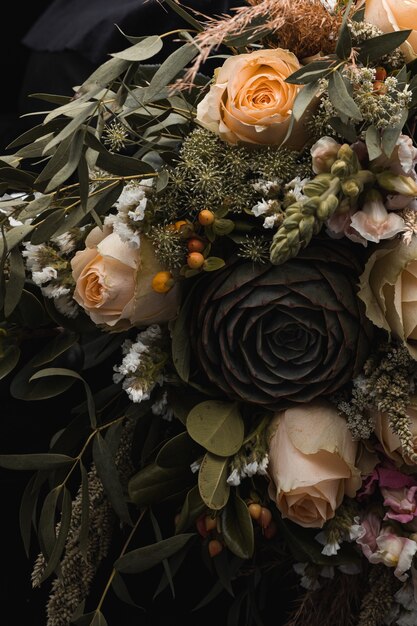 Вертикальный снимок крупным планом роскошного букета оранжевых и коричневых роз на черном