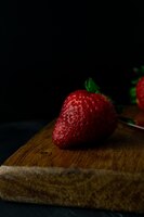 vertical closeup shot of fresh ripe strawberries on a wooden board