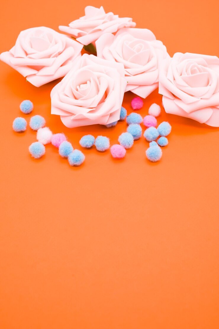Free Photo vertical closeup shot of pink roses and pompons isolated on orange background with copy space