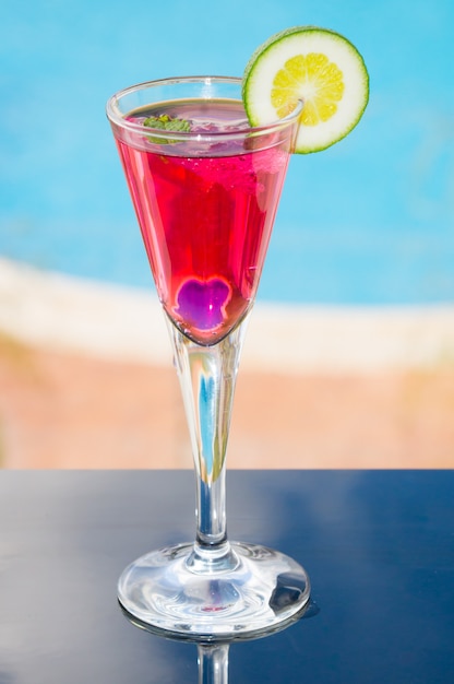 Vertical closeup shot of red cocktail with a slice of lime