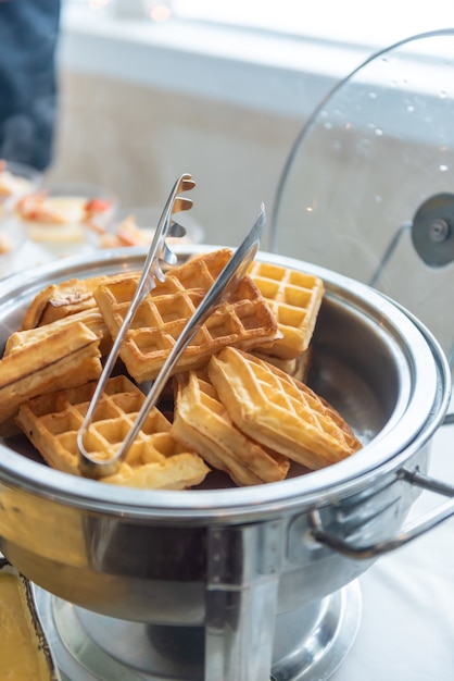 Vertical closeup shot of small waffles in a metal cooker on an event table