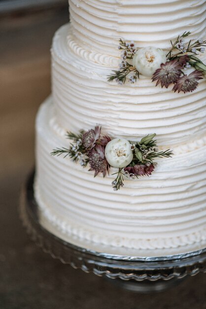 銀の大皿に花で飾られた3層のウエディングケーキの垂直のクローズアップショット