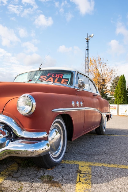 Vertical closeup shot of a vintage red car with a for sale sign