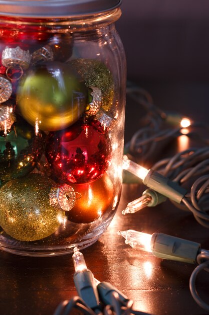 Vertical closeup view of colorful small baubles inside the glass jar