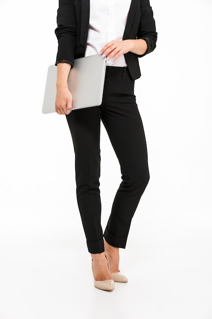 Vertical cropped image of body of business woman holding laptop computer over white wall