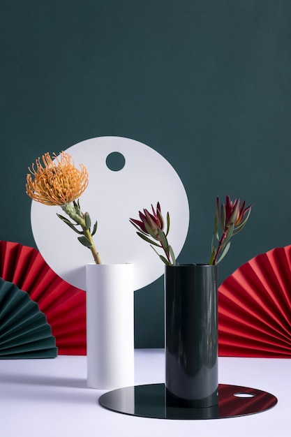 Vertical  of decorative vases with protea and billbergia flowers with Chinese folding fans