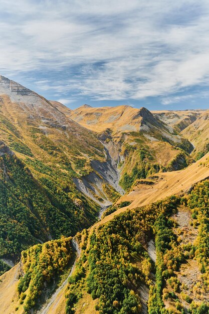 Vertical frame view of the gorge with a waterfall from the mountain plateau autumn in the mountains Idea for a banner or postcard with space for text travel to Georgia trekking in the mountains