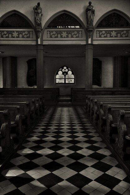 Vertical grayscale shot of the inside of a beautiful historical church taken from the altar side