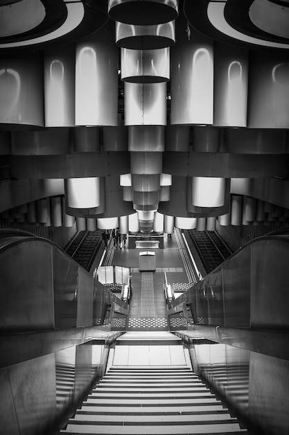 Foto gratuita scatto verticale in scala di grigi di una moderna stazione della metropolitana con scale mobili a bruxelles, belgio