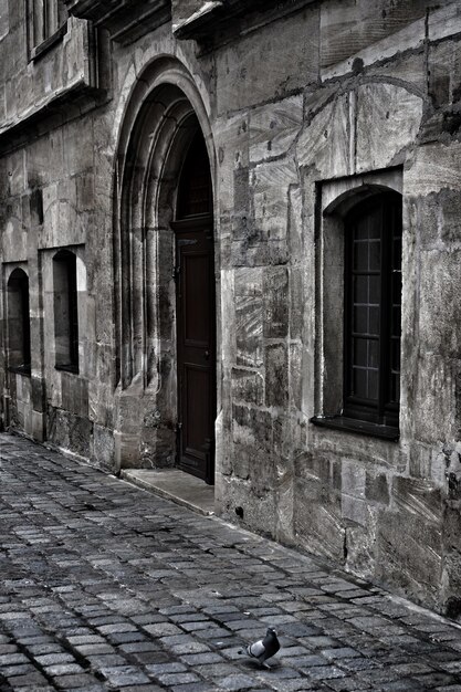 Vertical grayscale shot of an old historical building with an arch-shaped door