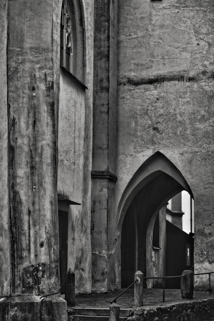 Vertical grayscale shot of an old stone historical building with an arch-shaped door