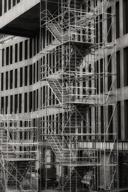 Вертикальный снимок лестницы в оттенках серого возле здания, используемого для реконструкции.