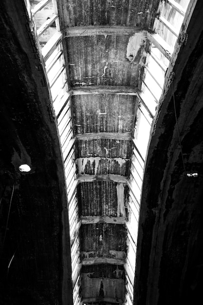 Vertical greyscale of a rusty ceiling of an ancient building during daytime