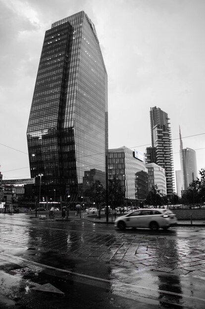 Vertical greyscale shot of a street with modern buildings in Milan, Italy