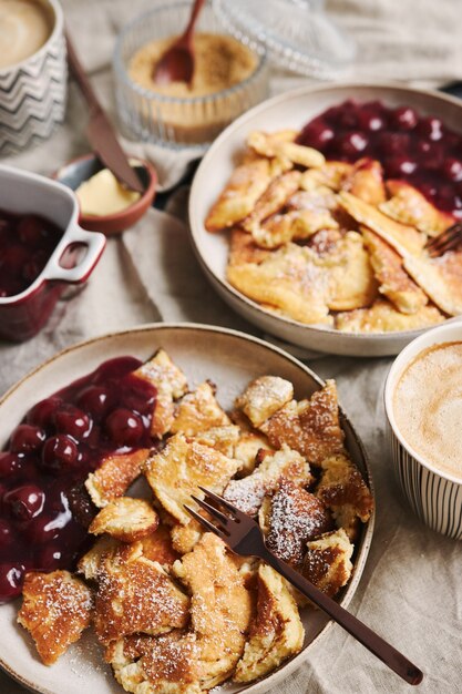 Vertical high angle shot of delicious fluffy pancakes with cherry and powdered sugar