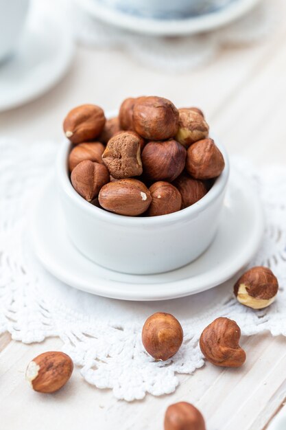 Vertical high angle shot of hazelnuts in a white cup