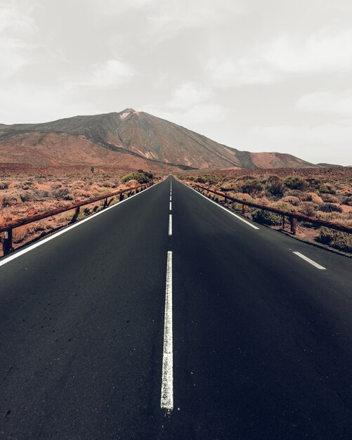 Vertical high angle shot of a highway surrounded by hills under the grey sky