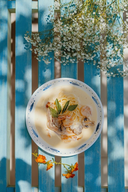 Free photo vertical high angle shot of pasta carbonara with mushrooms on a blue wooden bench