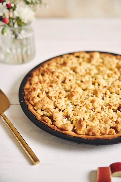 Foto gratuita colpo verticale ad alto angolo di un piatto di crostata di torta croccante rhabarbar e alcuni ingredienti su un tavolo