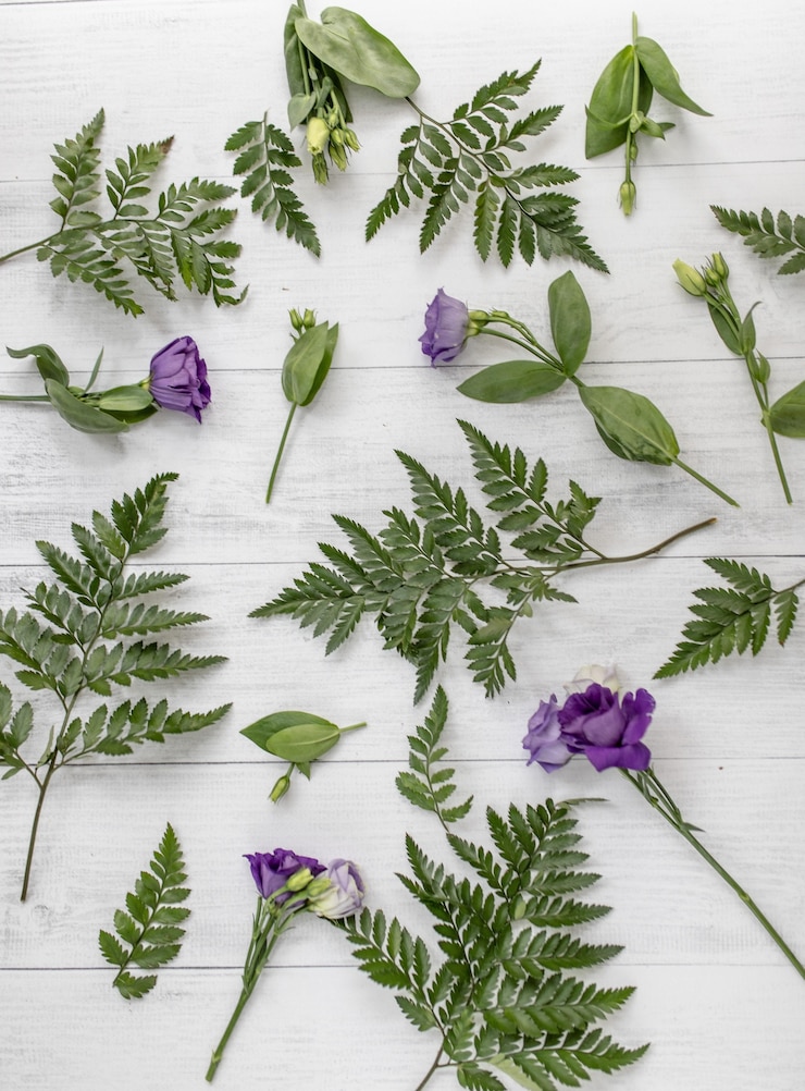 무료 Photo 보라색 lisianthus 꽃과 나무 표면에 녹색 잎의 수직 높은 각도 샷
