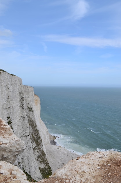 Vertical high angle shot of rocky cliffs near the sea in Dove, England