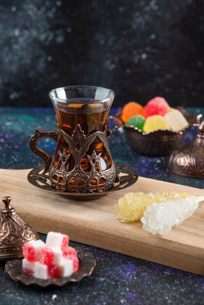 Вертикаль горячего чая и сладких конфет на деревянном баорде