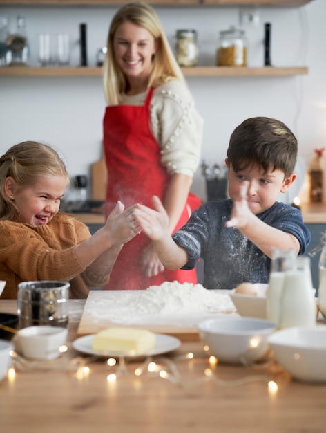 Free photo vertical image of children clasping using flour while baking cookies