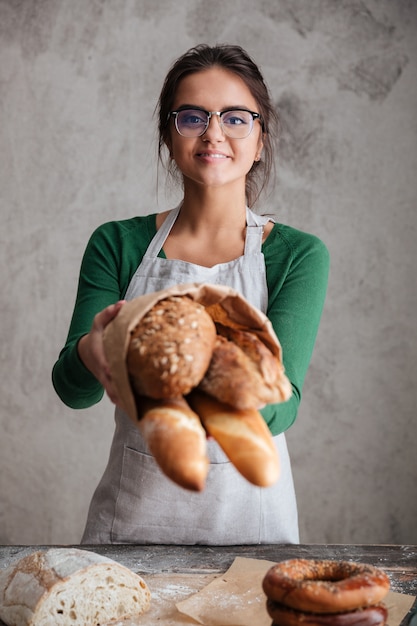 Vertical image of female baker showing bag with bread