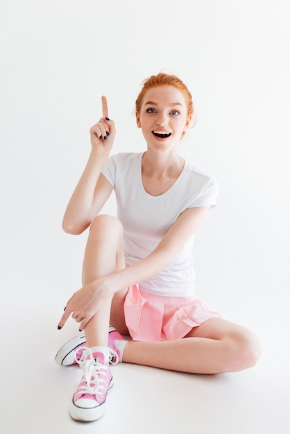 Vertical image of happy ginger girl having idea and looking