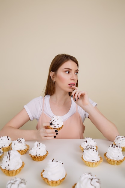 Immagine verticale della donna pensierosa dal tavolo con torte