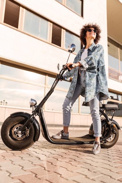 Free photo vertical image of pleased curly woman in sunglasses