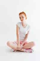 Free photo vertical image of pretty ginger girl sitting on the floor and looking