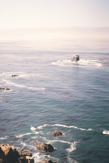 Vertical image of rocks on the ocean near a cliff shore