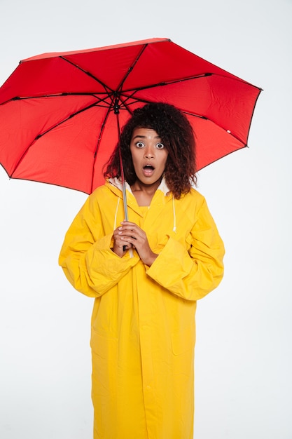 Vertical image of Shocked african woman in raincoat posing