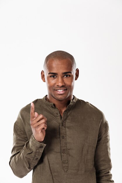 Vertical image of smiling african man pointing up and looking