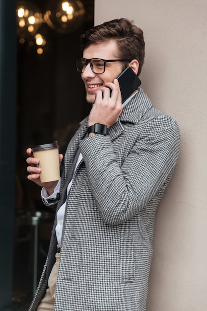 Vertical image of smiling businessman in eyeglasses and coat