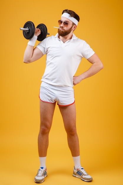 Vertical image of smoking sportsman holding dumbbell