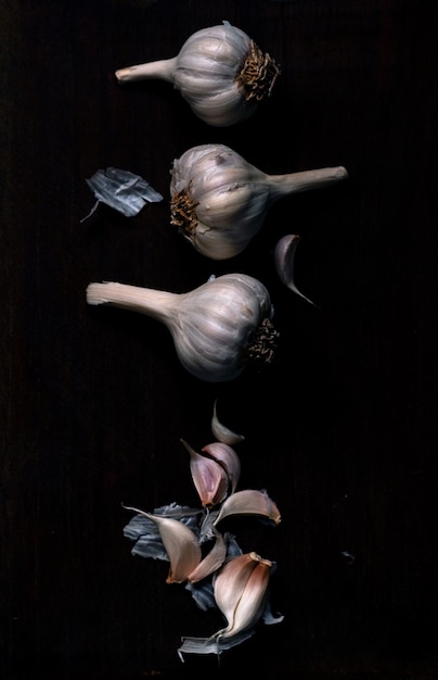 Free photo vertical isolated shot of garlics in a row on black