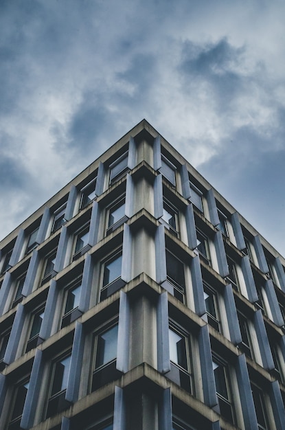 Vertical low angle shot of a blue and gray building under a cloudy sky