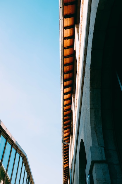 Vertical low angle shot of a grey concrete building in front of a building with glass facade