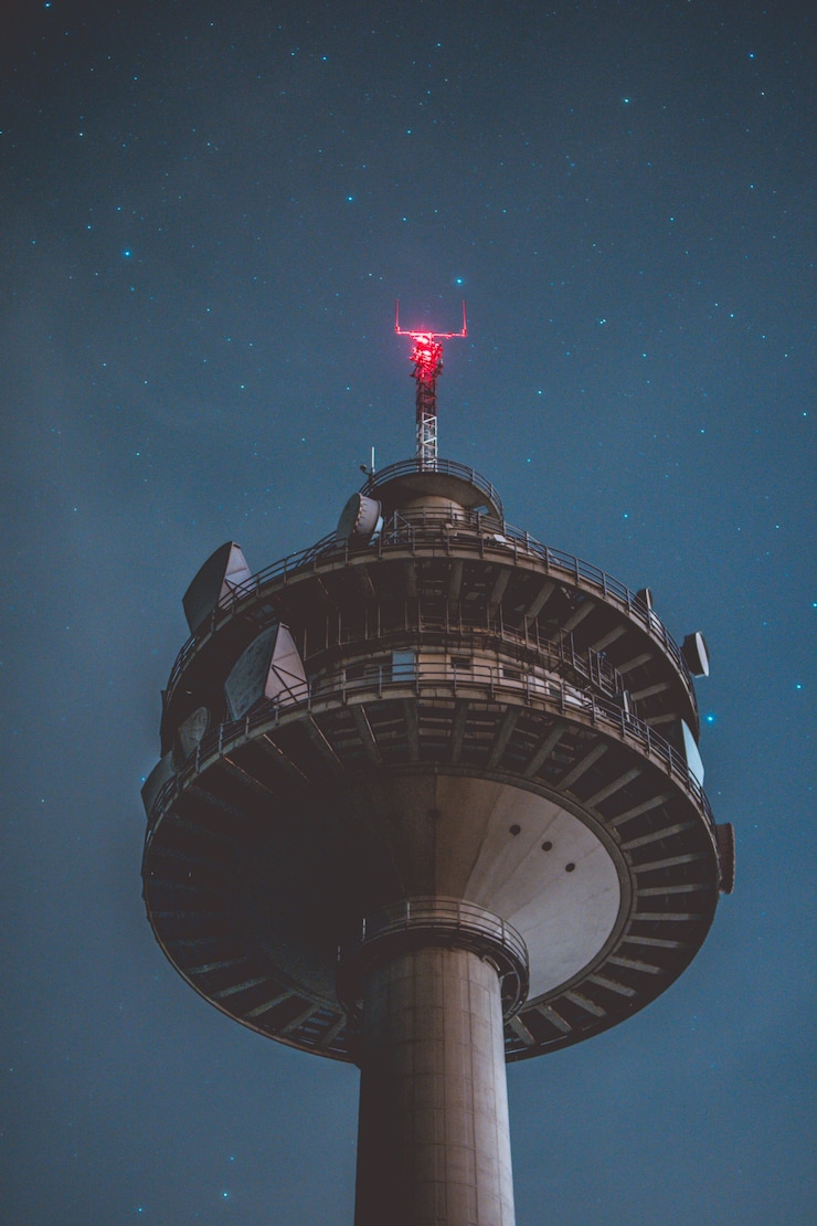 Free Photo vertical low angle shot of a grey tall tower at night with beautiful stars