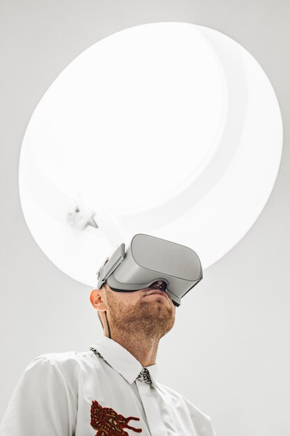 白色光の下で仮想現実ゴーグルを着ている人の垂直ローアングルショット