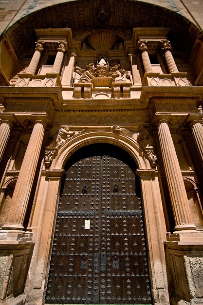 Вертикальный снимок стальных ворот на входе в величественное историческое здание под низким углом.