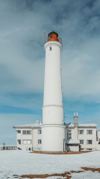 Vertical low angle of a white lighthouse under the cloudy sky
